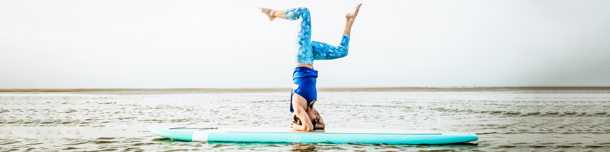 Frau macht Yoga auf einem Bord an der Lübecker Bucht