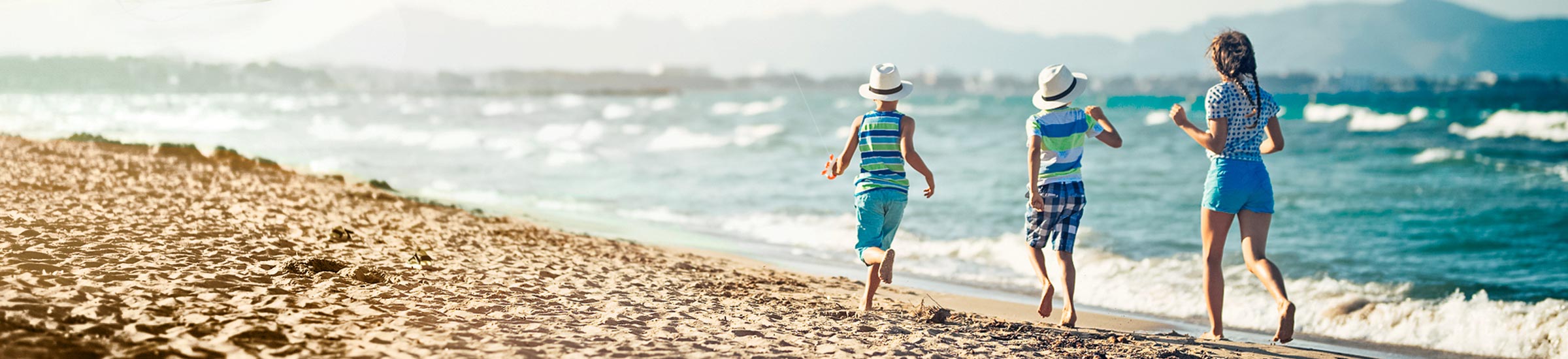 Drei Kinder lassen am Strand einen Drachen steigen