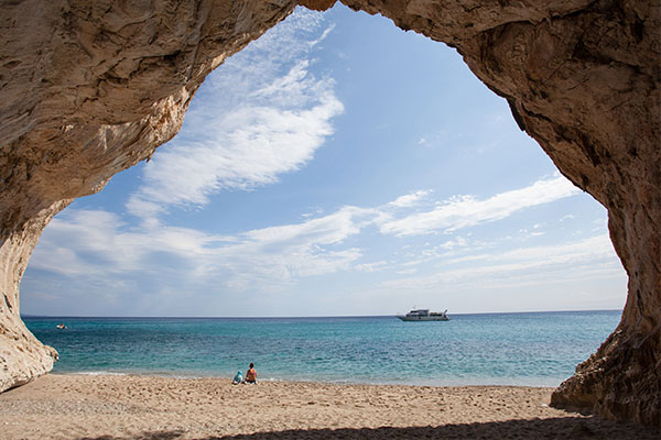 Blick aus einer Höhle auf ein Schiff - Sardinien-urlaub mit Kindern
