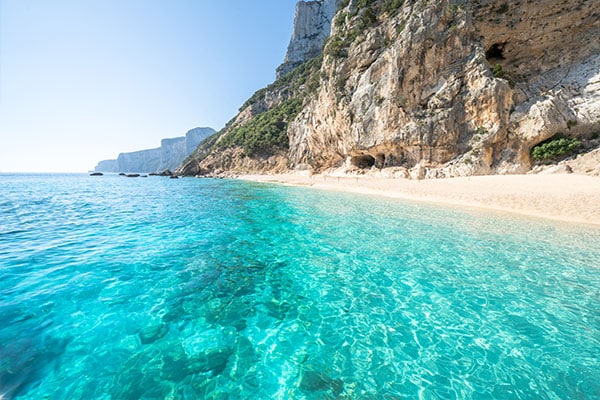 Azurblaues Wasser mit Strand und Felsen