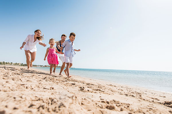 Familie mit Kindern am Strand vor blauem Meer