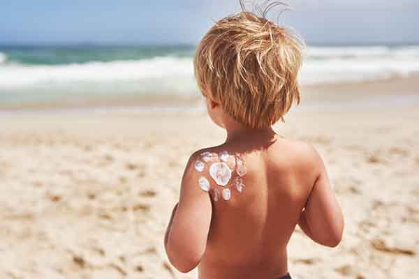 Kind am Strand mit Sonnencreme