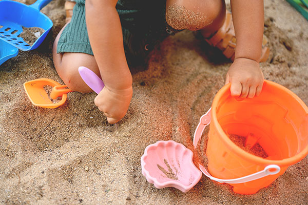 Kinder mit Strandspielzeug am Strand im Famillienurlaub