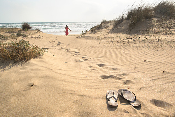 Frau am Strand mit Flip Flops am Sand