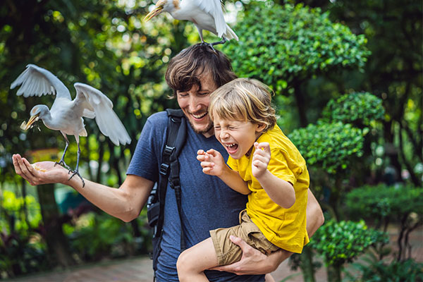 Vater und Kind mit Vögeln auf dem Arm