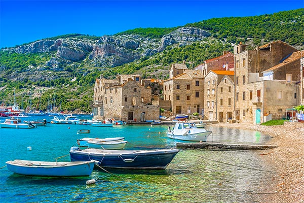 Die Stadt Komiza auf der Inseln Vis in Dalmatien mit kleinen Booten und Bergen im Hintergrund
