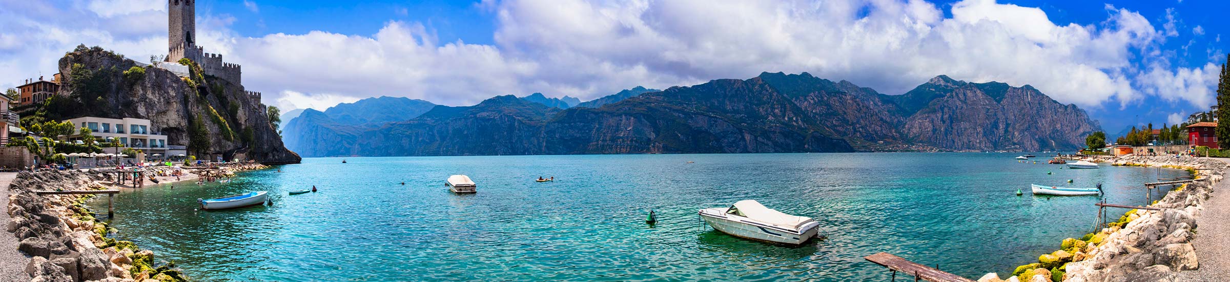 Panoramablick auf den Gardasee mit Bergen im Hintergrund und kleinen Booten