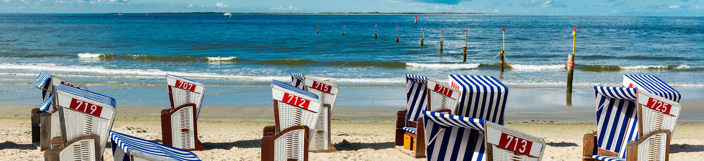 Blau-weiße Srtrandkörbe am Strand von Norderney mit der Nordsee im Hintergrund