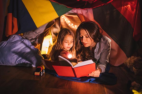 Mutter und Kind lesen Gruselgeschichten im Zelt