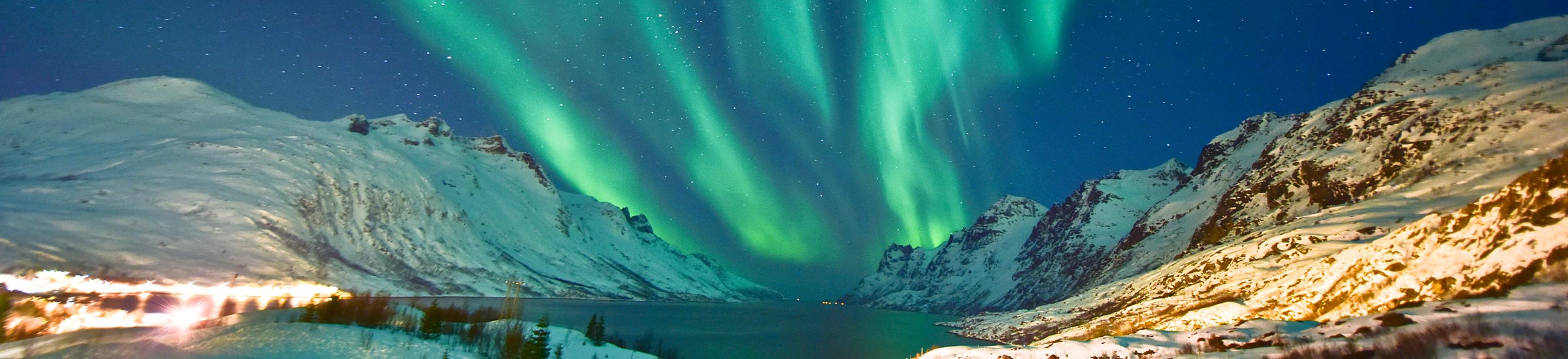 Polarlichter umgeben von Bergen mit Schnee in Norwegen