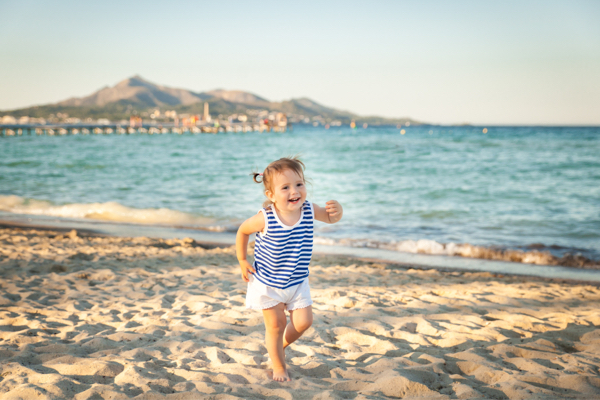 Kleines Kind rennt am Strand auf Mallorca
