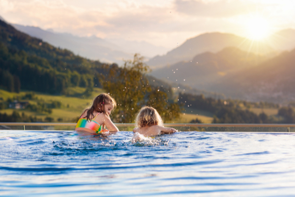 Zwei Kinder genießen im Pool den Bergblick