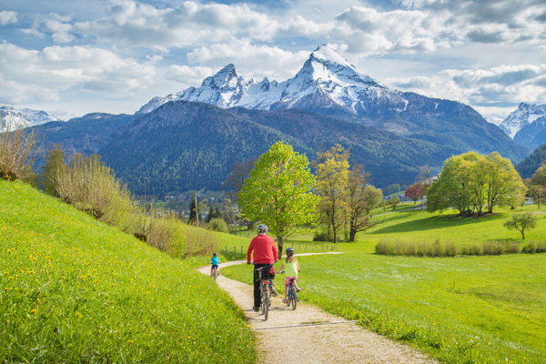 Familie fährt Fahrrad mit Blick auf die Alpen
