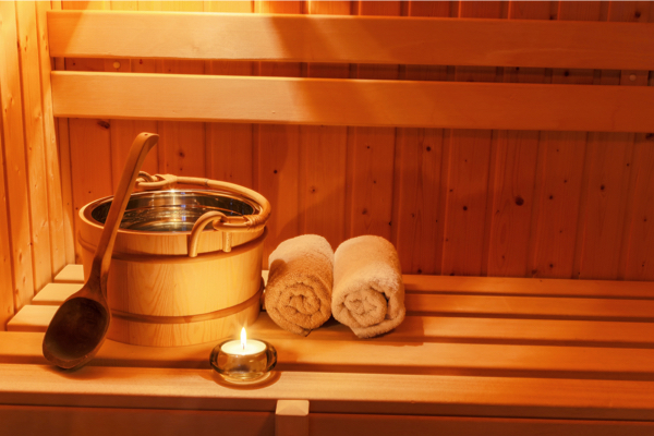 Aufgussbehälter, Handtücher und Kerze in einer Sauna
