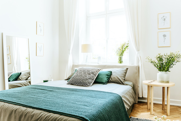 Schlafzimmer mit gemütlicher Einrichtung: Bett und petrolfarbener Tagesdecke