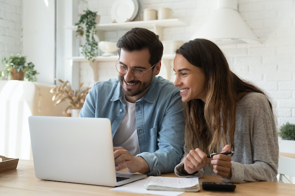 Glückliches Paar schaut gemeinsam auf einen Laptop , wo es z.B. eine Website erstellt