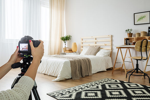 Schlafzimmer mit einer Kamera im Vordergrund, mit der ein Foto der Einrichtung gemacht wird