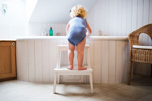 Kind auf Tritthocker im Badezimmer einer Ferienwohnung