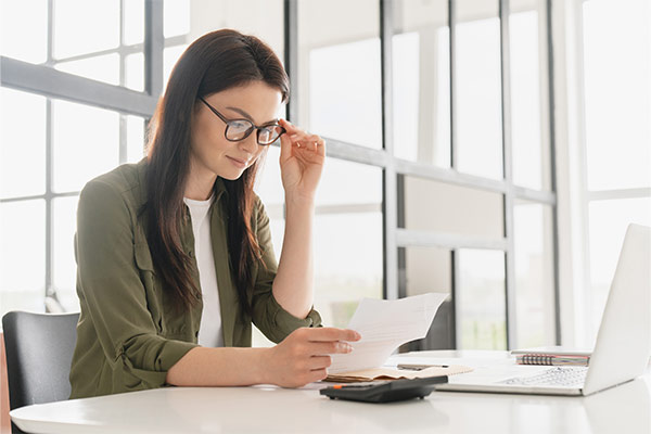 Junge Frau, die am Laptop sitzt und Kosten kalkuliert