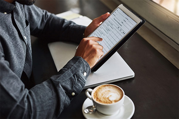 Mann, der mit Tablet an einem Tisch sitzt und einen Fragebogen erstellt